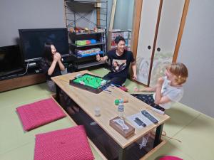 a group of people sitting around a table playing a video game at Stay Inn KOTO in Kyoto