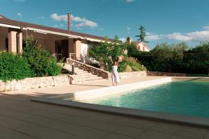 a woman is standing in front of a swimming pool at B&B La Ferula in Altamura