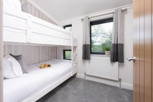 a bedroom with two bunk beds and a window at Maple Lodge, 20 Roadford Lake Lodges in Lifton
