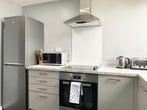 a kitchen with a stove and a microwave at Pentland House - Lovely 2 bed flat in East Kilbride in East Kilbride