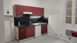 Appartement 3 - T2 60m2 - Standing, moderne et tout équipé - Carmes-Renforts , Toulouse في تولوز: مطبخ مع دواليب حمراء ومغسلة
