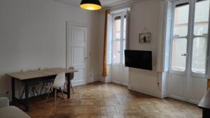 Appartement 3 - T2 60m2 - Standing, moderne et tout équipé - Carmes-Renforts , Toulouse في تولوز: غرفة معيشة مع طاولة وتلفزيون