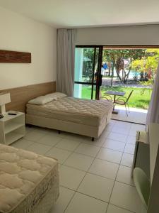 a bedroom with two beds and a table and a window at Suíte com varanda no iloa - sem enxoval in Barra de São Miguel