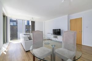 ロンドンにあるCity Waterview 2B2B Lux Apartmentのリビングルーム(ガラスのテーブル、椅子付)