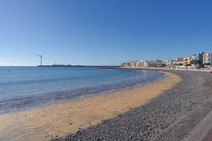 a sandy beach with buildings and the ocean at Las Afortunadas , Playa Arinaga 1ºA in Arinaga