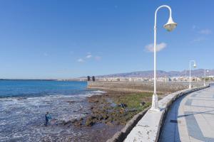 a street light next to a beach with people in the water at Las Afortunadas , Playa Arinaga 1ºA in Arinaga