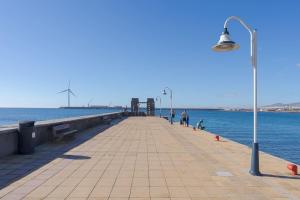 a pier with a street light and people walking on it at Las Afortunadas , Playa Arinaga 1ºA in Arinaga