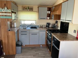 cocina con armarios blancos y fogones en Jemmima's Caravan with Smart TV and WIFI en Rhyl