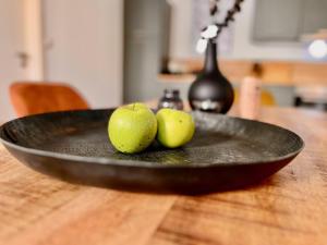 a black plate with two apples on a wooden table at MEL&BENS Loft-Appartements Terrasse Weserstadion in Bremen