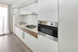 a kitchen with white cabinets and a stove top oven at Light & Airy 3 Bd CBD Apt: BalconyTramWifi/Parking in Adelaide