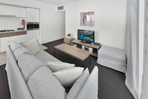 a living room with a white couch and a television at Light & Airy 3 Bd CBD Apt: BalconyTramWifi/Parking in Adelaide