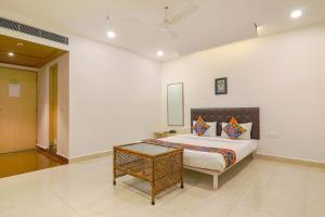 a bedroom with a king sized bed and a chair at FabHotel Aamantran & Banquet Halls in Hyderabad