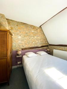 - une chambre avec un grand lit et un mur en pierre dans l'établissement Hostellerie Du Chateau, à Châteauneuf