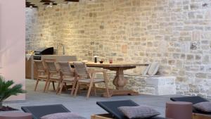 een houten tafel en stoelen in een kamer met een bakstenen muur bij Jasmine Villa, with curated design, By ThinkVilla in Perama