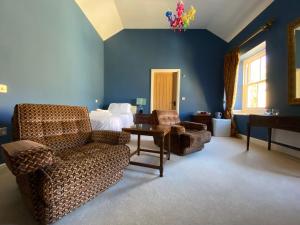 a bedroom with a bed and a couch and chairs at Harbour Inn in Amble