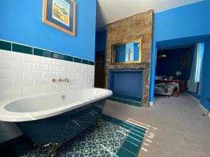 uma casa de banho com uma banheira branca e paredes azuis em Harbour Inn em Amble