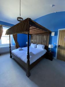 a bedroom with a canopy bed in a blue room at Harbour Inn in Amble