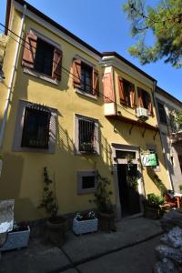 ein gelbes Gebäude mit Topfpflanzen davor in der Unterkunft Olivia1845 Guest House Ayvalık in Ayvalık