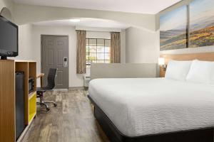 a hotel room with a bed and a flat screen tv at Days Inn by Wyndham Fulton in Fulton