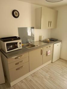 una pequeña cocina con microondas y fregadero en Suite privée avec BALNEO (Jacuzzi ou baignoire). en Yvetot