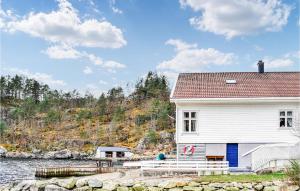 een wit huis naast een waterlichaam bij Amazing Home In Vanvik With Kitchen in Sand