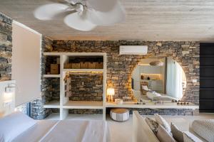 1 dormitorio con pared de piedra y espejo en Akra Grammeno Beachfront Villas, en Palaiochóra