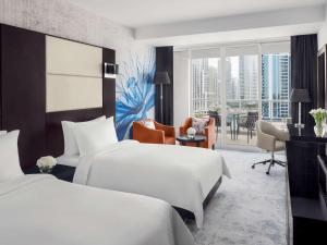 a hotel room with two beds and a desk at Mövenpick Hotel Jumeirah Lakes Towers Dubai in Dubai