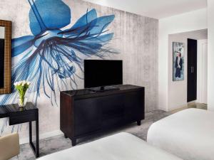 a bedroom with a tv and a painting of a flower at Mövenpick Hotel Jumeirah Lakes Towers Dubai in Dubai