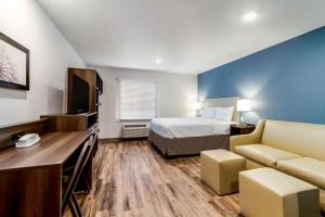 WoodSpring Suites Harrisburg Linglestown في هاريسبورغ: غرفه فندقيه بسرير واريكه