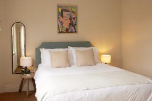 1 dormitorio con 1 cama blanca grande y 2 lámparas en The Grosvenor Arms, en Hindon