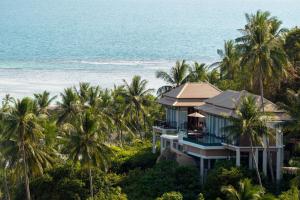 a house on the beach with palm trees and the ocean at Banyan Tree Samui in Lamai