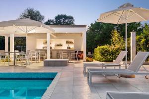a pool with chairs and umbrellas next to a house at TRYP by Wyndham Corfu Dassia in Dassia
