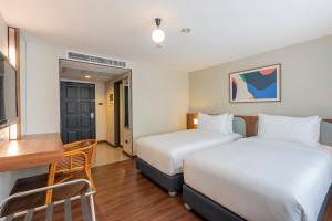 a hotel room with two beds and a desk at Arck Hotel in Bangkok