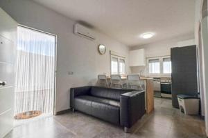 ein Wohnzimmer mit einer schwarzen Couch und einer Küche in der Unterkunft Villa Adrián in Las Palmas de Gran Canaria