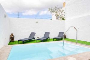 ein Pool mit drei Stühlen neben einem Gebäude in der Unterkunft Villa Adrián in Las Palmas de Gran Canaria