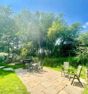 a patio with tables and chairs in a garden at Tree Tops Holiday Let & Sauna South Downs West Sussex Sleeps 10 in Hardham