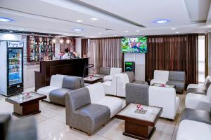 a waiting room with couches chairs and a television at Séréna Hôtel in Douala