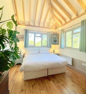 Tree Tops Holiday Let & Sauna South Downs West Sussex Sleeps 10 في Hardham: غرفة نوم مع سرير أبيض كبير في غرفة