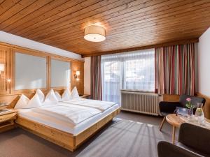 een slaapkamer met een groot bed en een groot raam bij Hotel Kössler in Tux