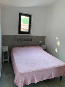 um quarto com uma cama rosa e uma janela em Vigna Sul Mare em Marina Palmense