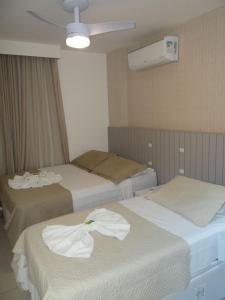 duas camas num quarto de hotel com toalhas em Resort em Arraial do Cabo, Momentos inesquecíveis em um apartamento de luxo com 2 quartos, 2 BANHEIROS e 2 vagas de carro entre a praia e a lagoa em Arraial do Cabo