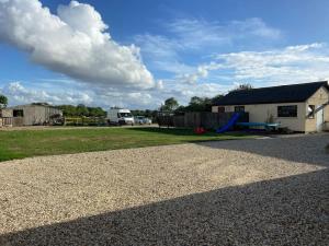 a gravel driveway with a house and a building at Thames Cottage, Old Mill Farm, Cotswold Water Park in Cirencester