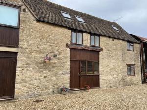 an old brick building with two garage doors at Thames Cottage, Old Mill Farm, Cotswold Water Park in Cirencester