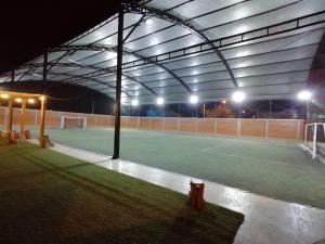 a tennis court lit up at night with lights at Hotel Campestre Casa Laredo in Chao