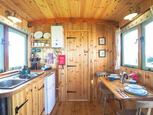 a kitchen with wooden walls and a table with chairs at Trenewydd Farm Holiday Cottages in Cardigan