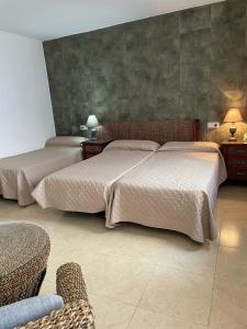 two beds in a bedroom with two chairs and a couch at La Albarizuela in Jerez de la Frontera