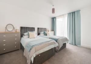 a bedroom with two beds and a dresser and a window at Abbey View in Leiston