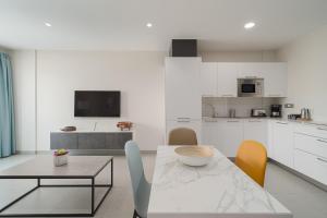 a white kitchen with a table and chairs at Las Afortunadas - Playa Arinaga 2ºD in Arinaga