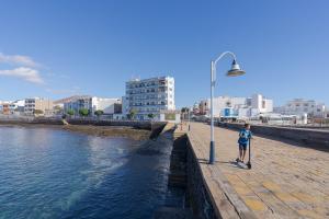 a boy standing next to a street light next to a river at Las Afortunadas - Playa Arinaga 2ºD in Arinaga