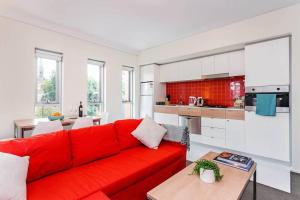 a living room with a red couch and a kitchen at City Centre Apt - 3 Bed/Parking/CBD/WiFi in Adelaide